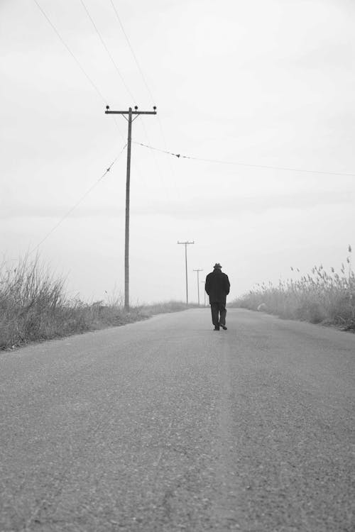 Silhouette of a Man Walking on the Road Alone 