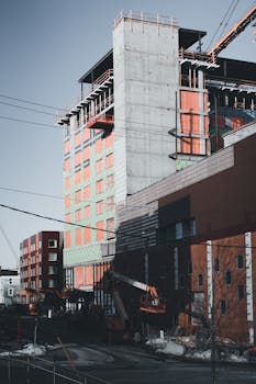 High-rise building construction with scaffolding in an urban cityscape.
