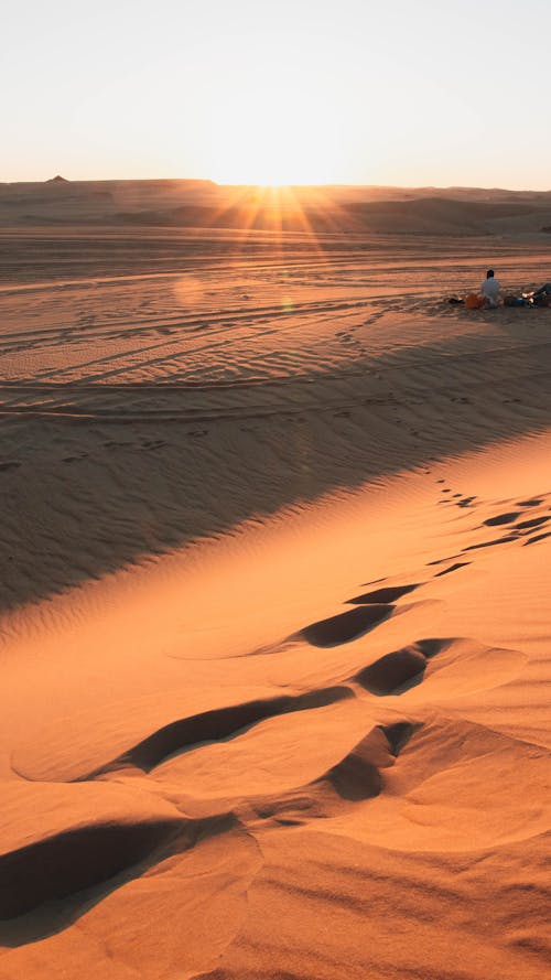 Sun Setting over a Desert with Footprints in the Foreground