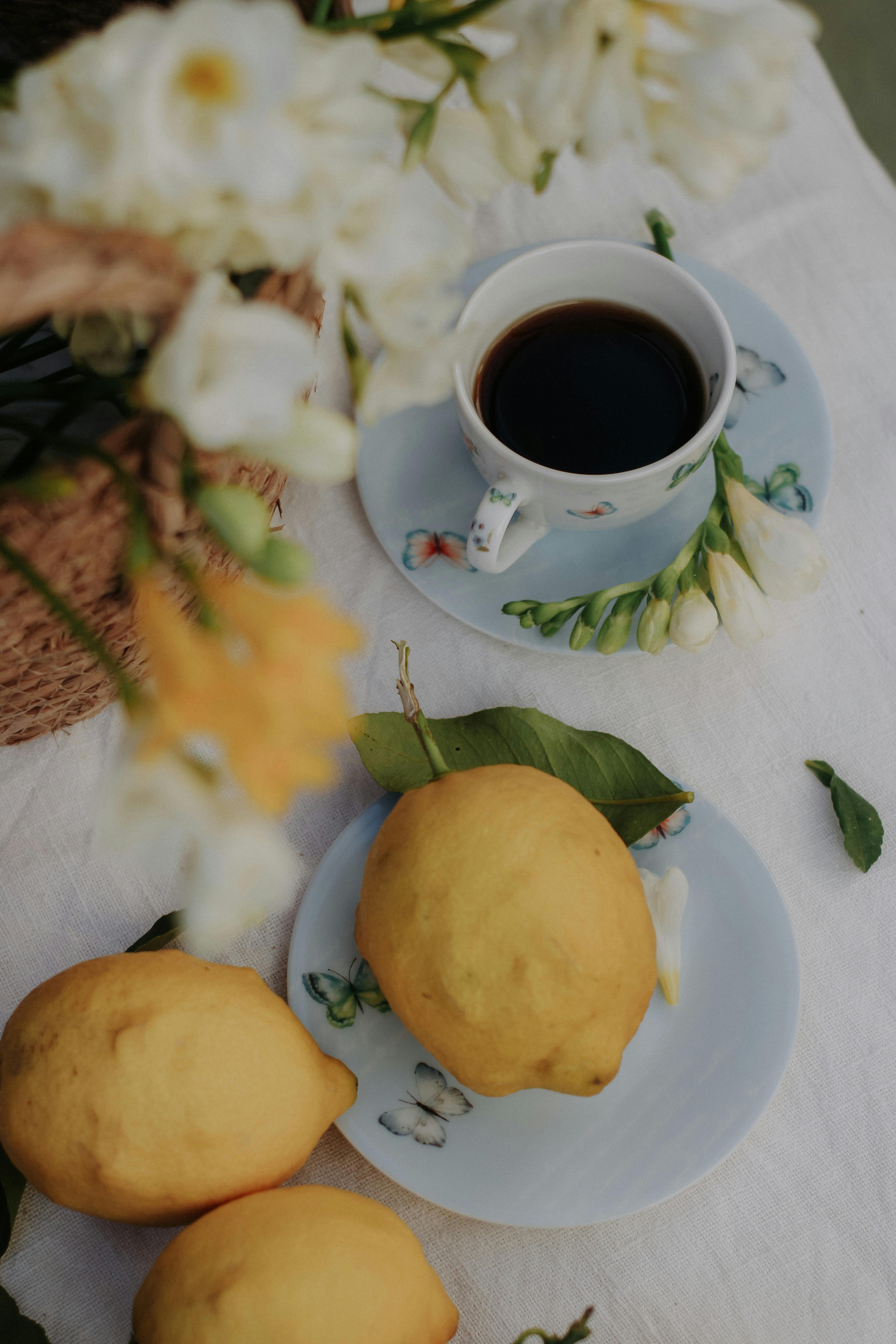 Artistic composition of fresh lemons, coffee, and flowers on a table.