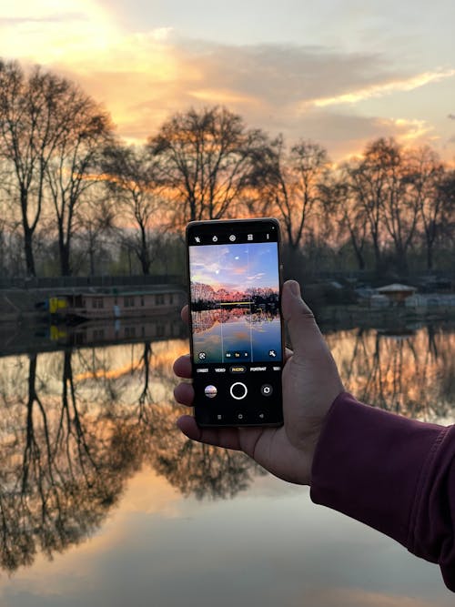 Person Taking a Photo of a Lake at Sunset
