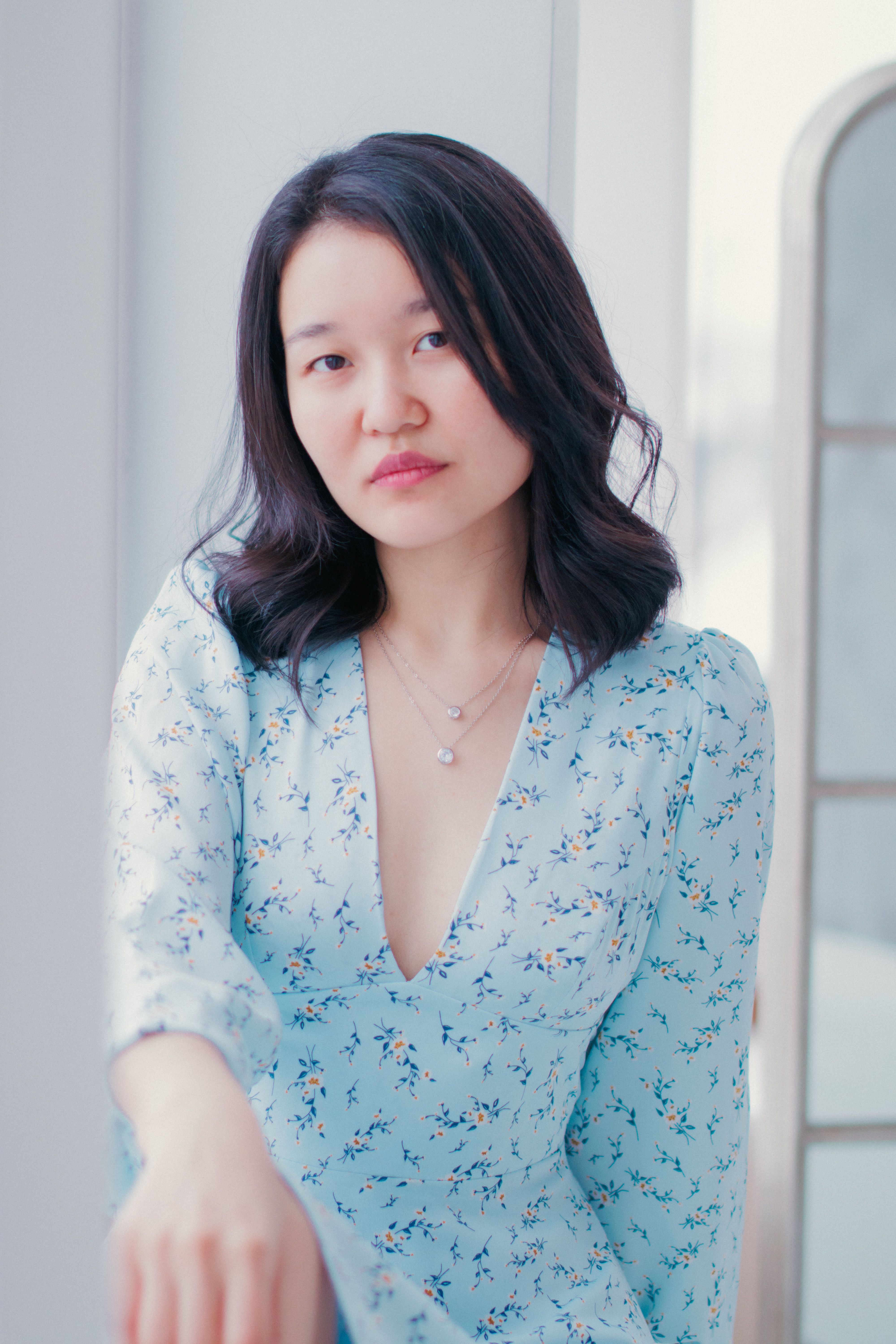 Portrait of a young woman in a floral blue dress, exuding elegance and style.
