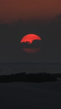 Stunning red sunset over a serene ocean with dramatic clouds and reflections.