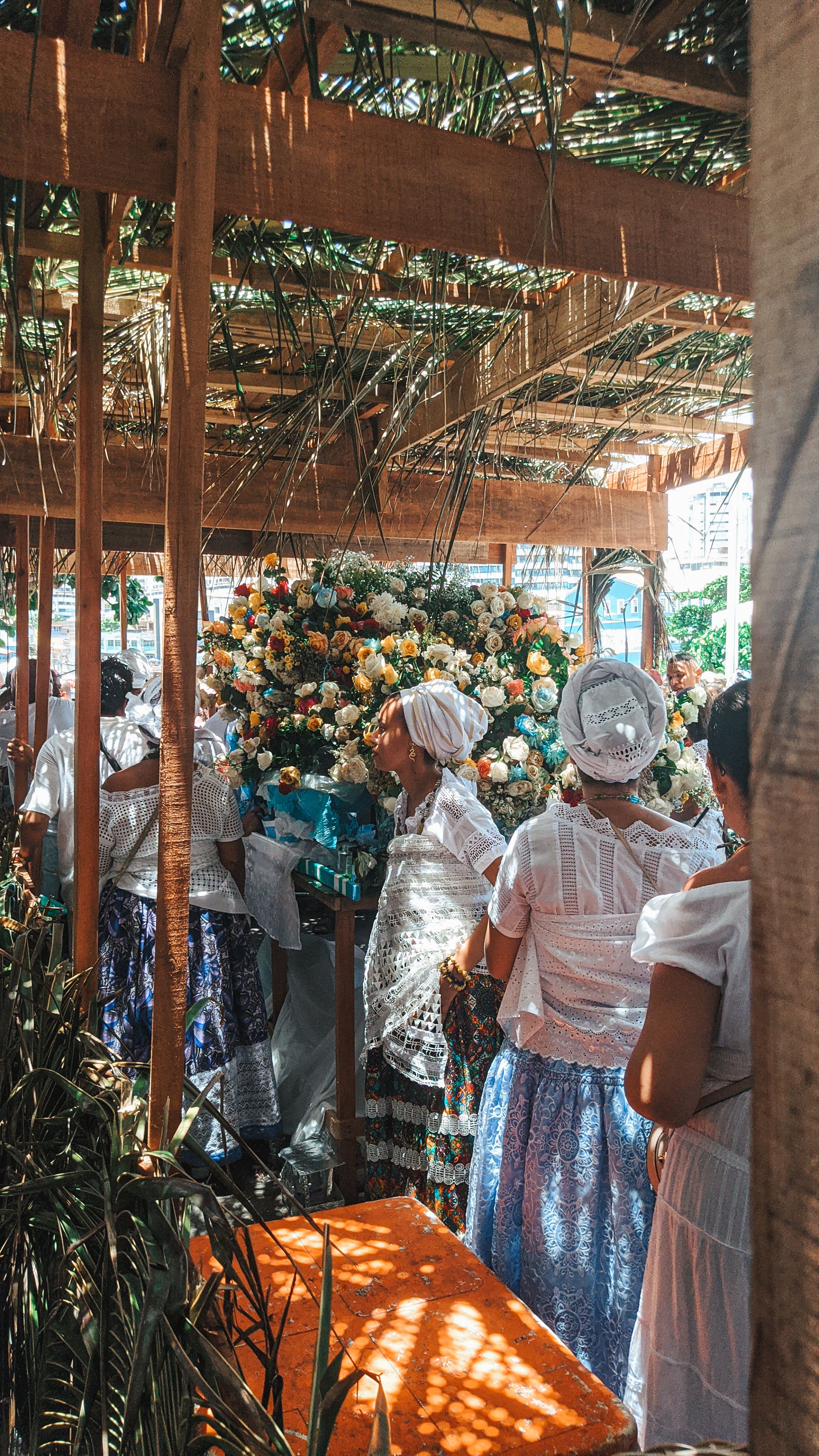 Women in traditional attire celebrate with colorful flowers in Salvador, Brazil.