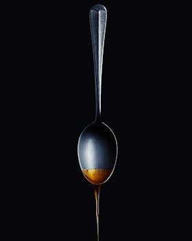 A creative shot of honey dripping from a spoon against a black backdrop, showcasing contrast and design.