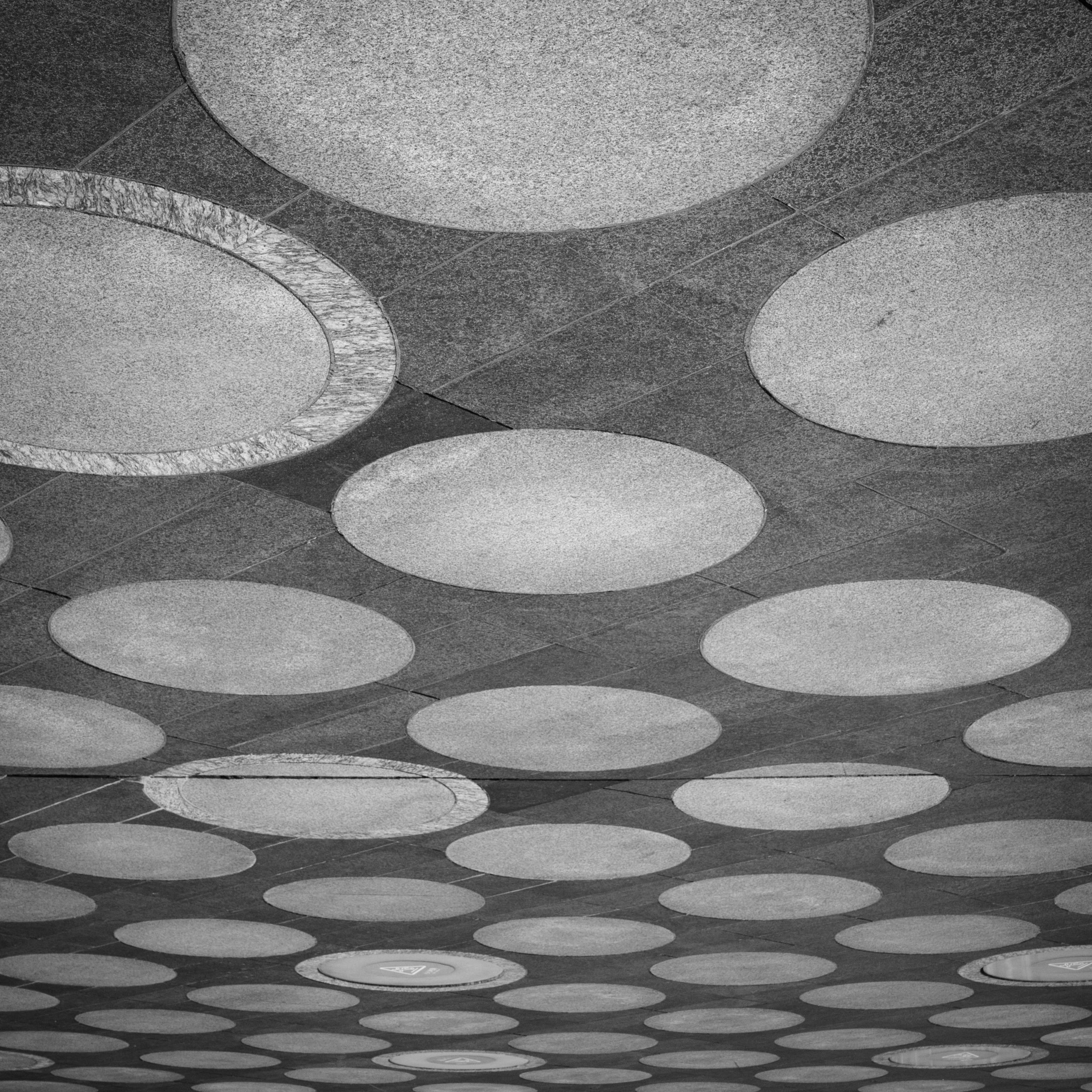 Black and white abstract ceiling showcasing repetitive circular patterns and geometric symmetry.