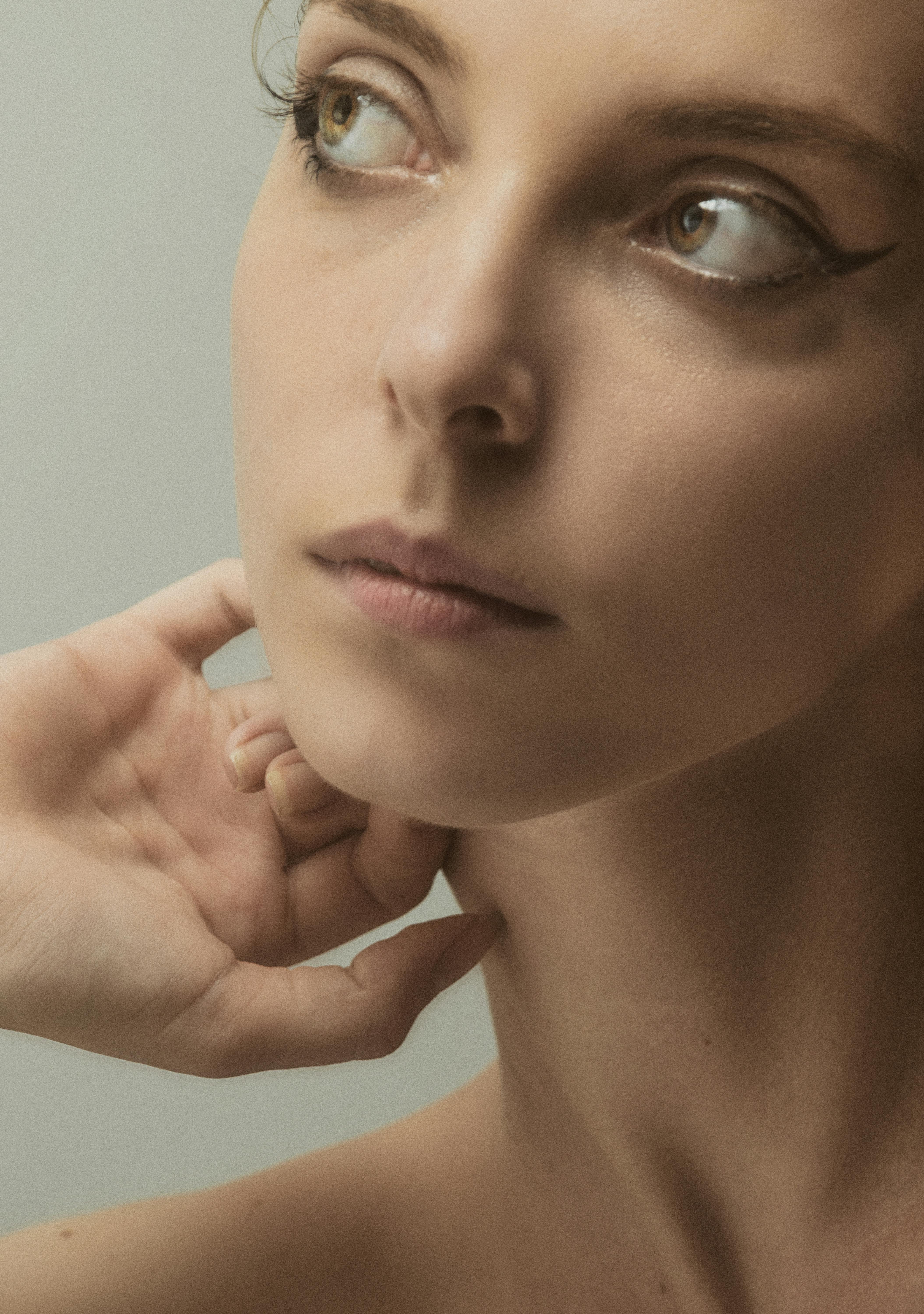 Close-up portrait focusing on a woman's thoughtful expression and delicate hand pose.