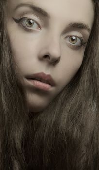 A detailed portrait of a young woman with striking eyes and long brown hair.