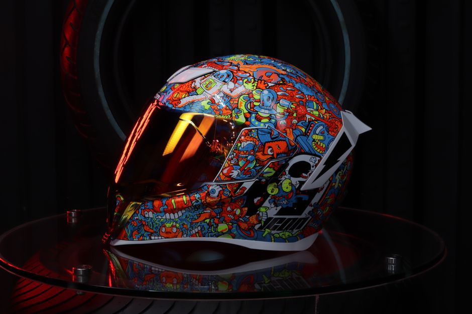 A vibrant motorcycle helmet with artful graphics showcased on a glass display.