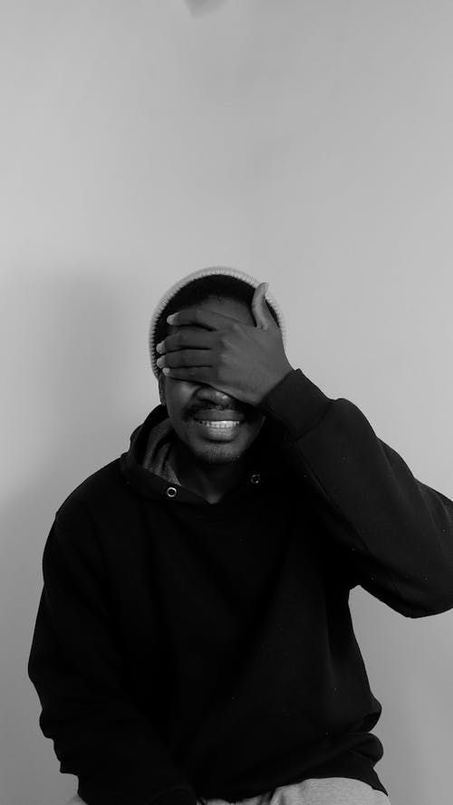 Black and White Picture of a Young Man Sitting and Holding His Hand over His Eyes 