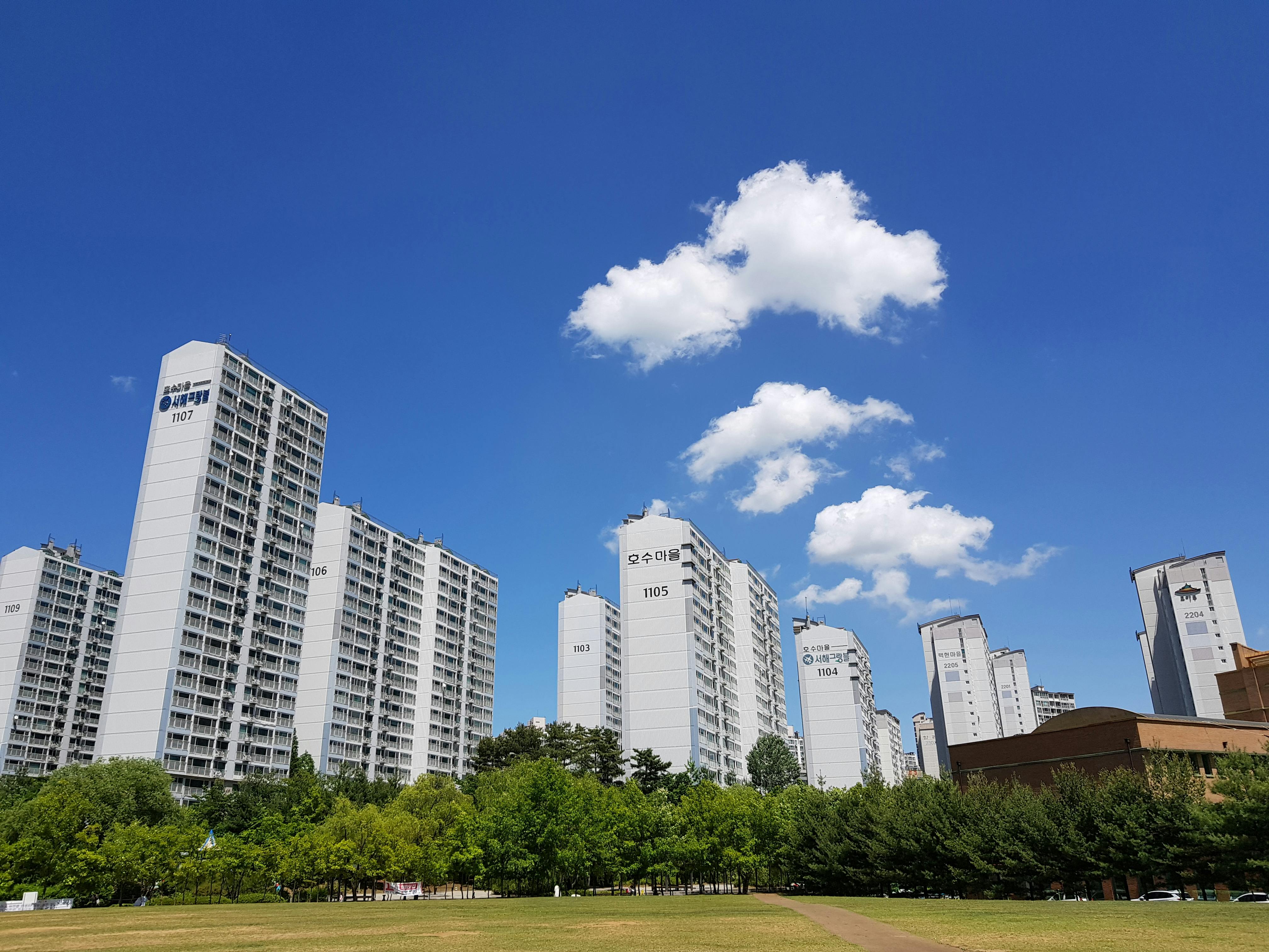 Skyline of high-rise apartments in Yongin with clear blue sky and clouds.