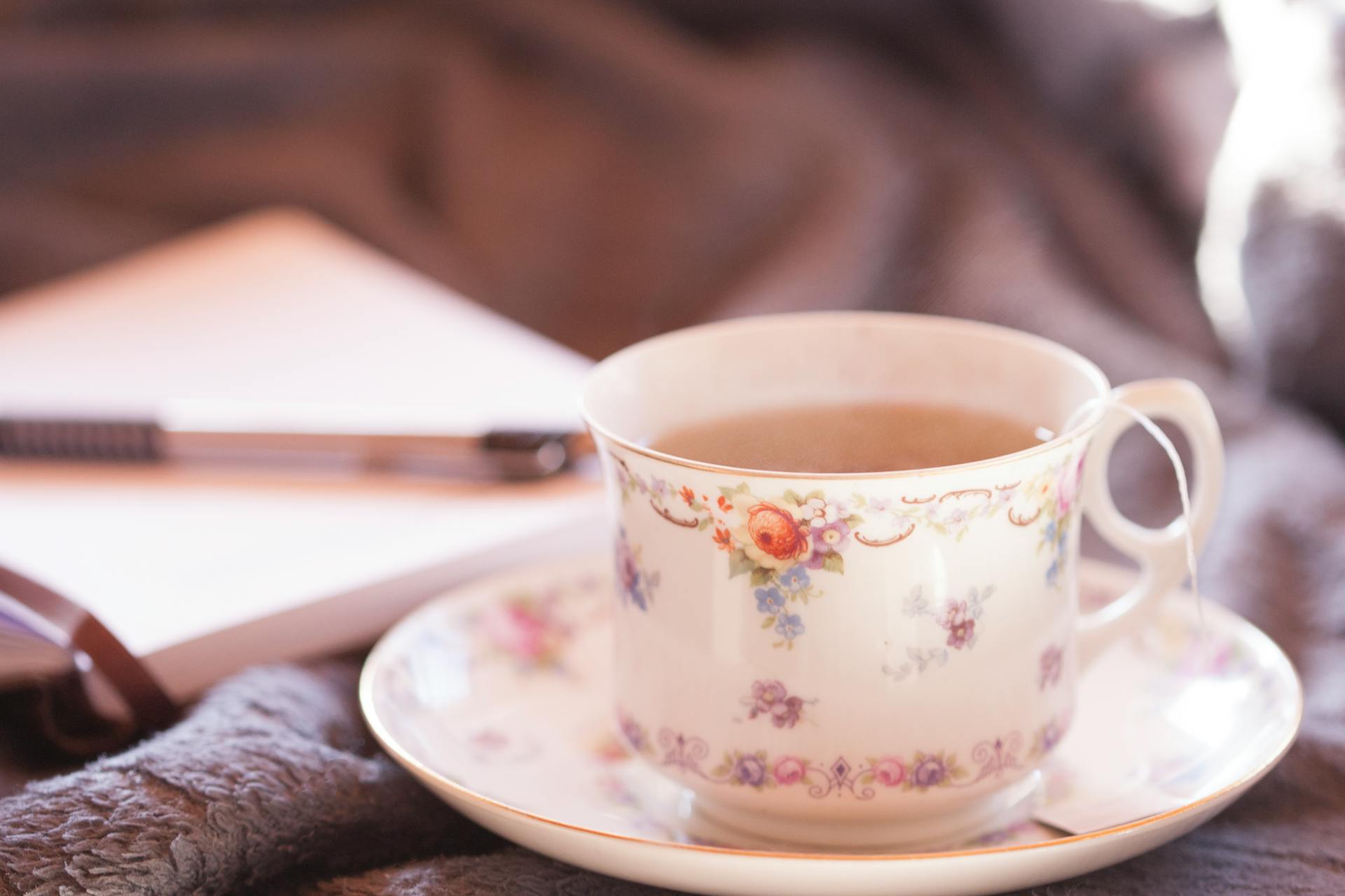 Selektiv fokusfotografering av vit och mångfärgad blomkremisk tekopp på tallrik fylld med kaffe