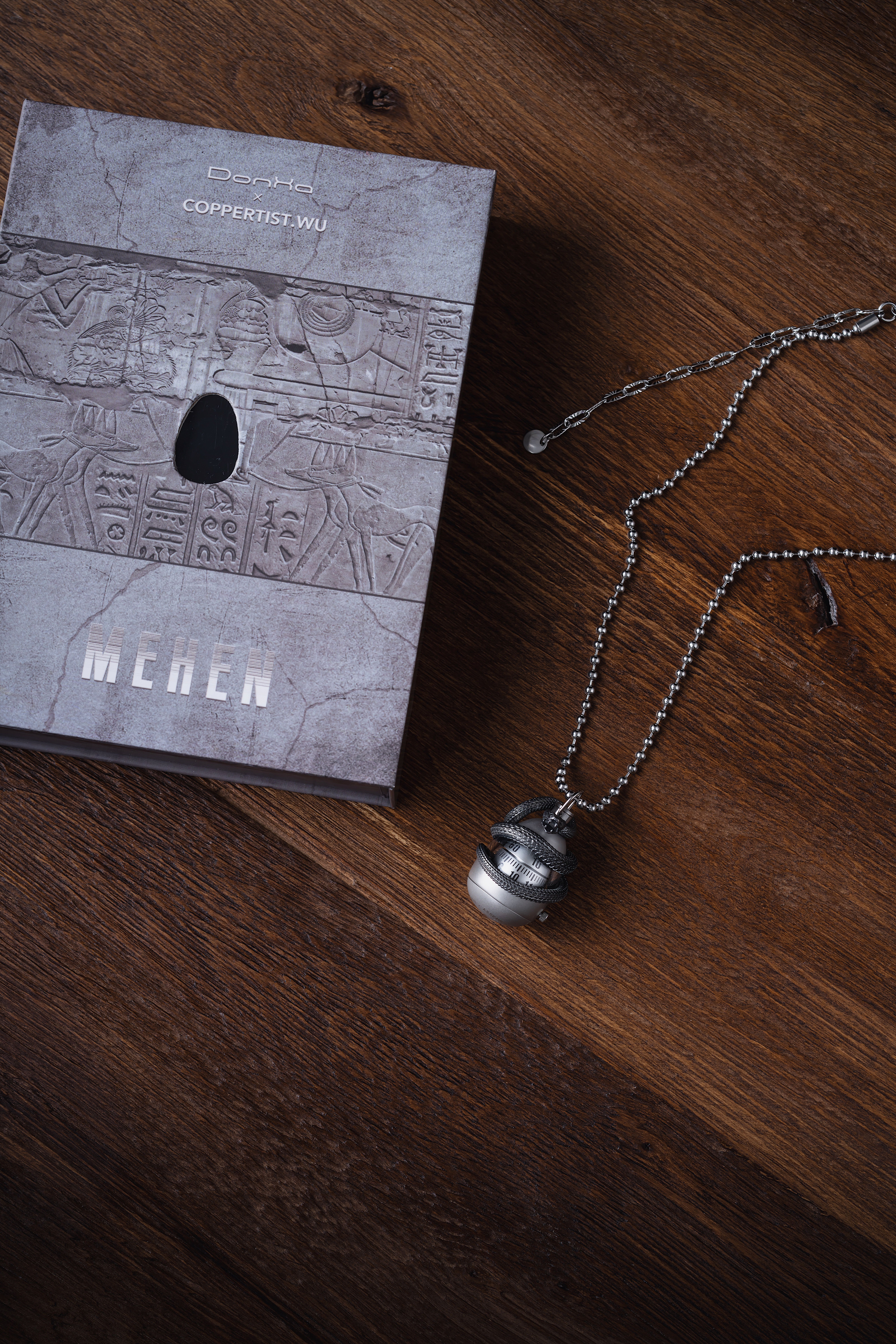 Stylish silver necklace displayed on a wooden surface with a decorative box.