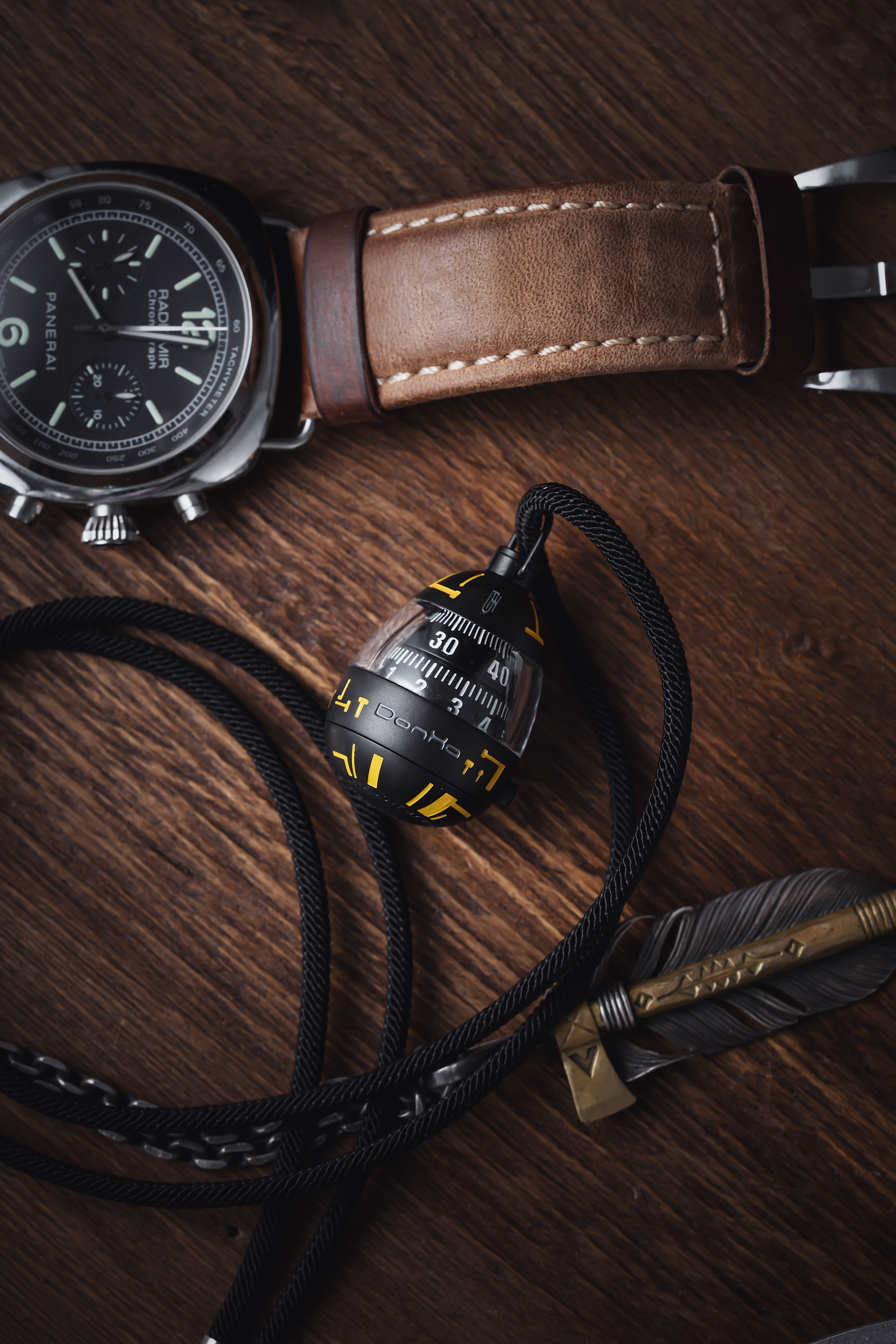 Stylish wristwatch and compass on a brown wooden table, perfect for adventurers and elegance lovers.