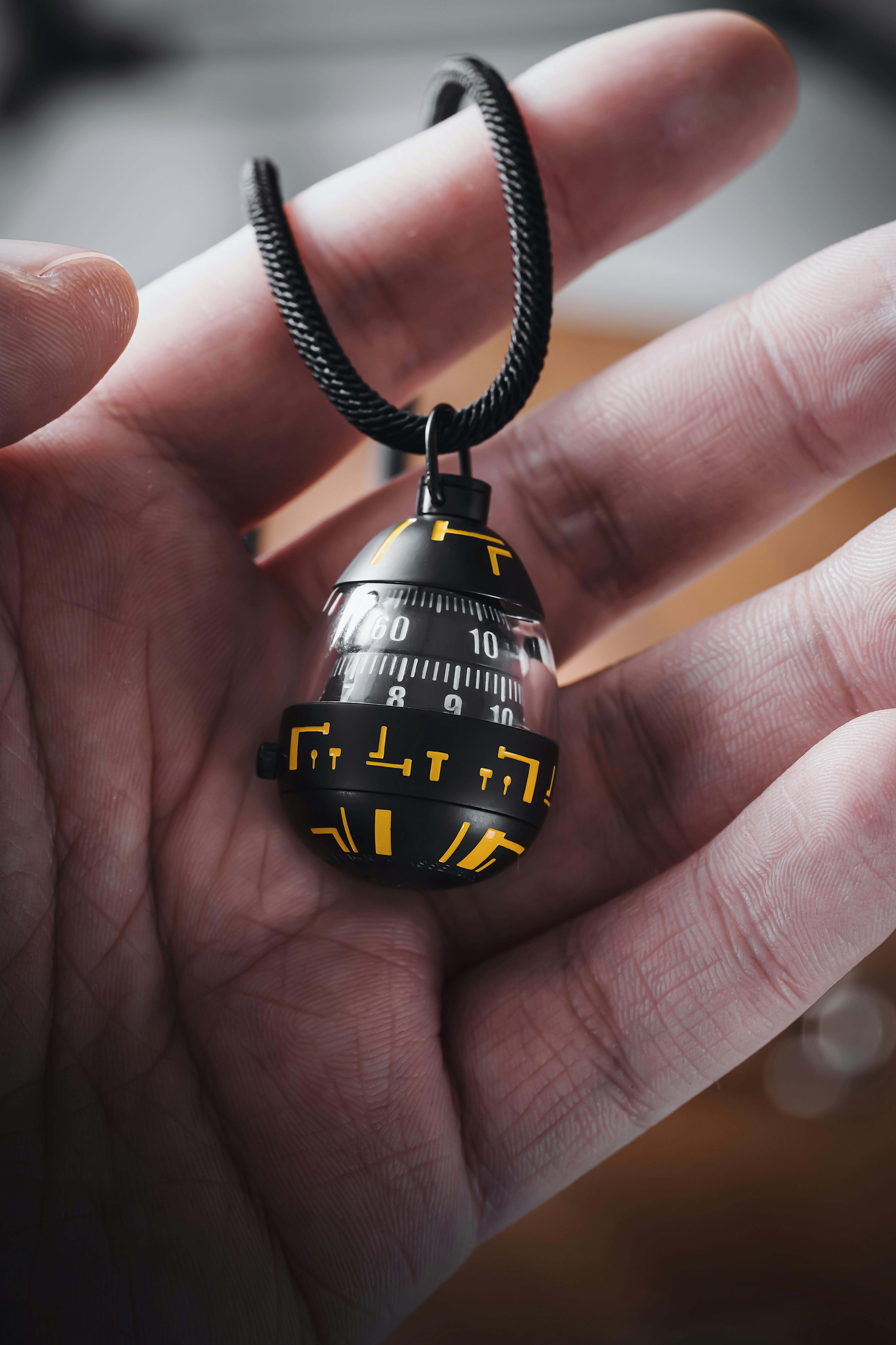 Detailed close-up of a unique egg-shaped pendant held in a hand, showcasing intricate designs.