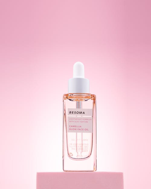 Close-up of a Glass Bottle of a Face Oil Standing on Pink Background 