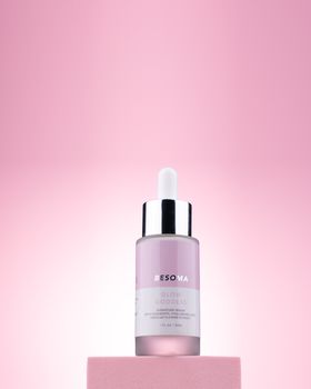 Sophisticated skincare serum on a pink pedestal with a soft backdrop.