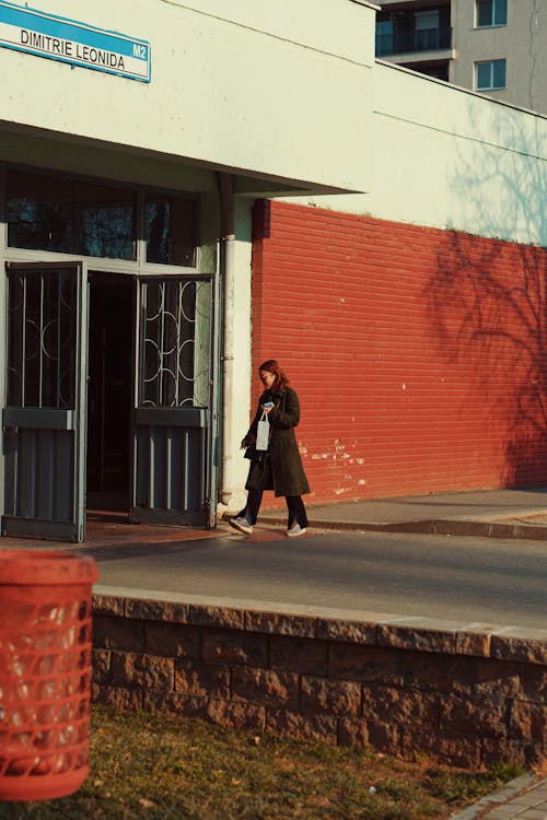 Woman Walking by a Red Wall 