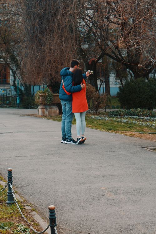 Free Adorable couple embraces while taking a selfie in a scenic park setting, capturing a moment of love. Stock Photo