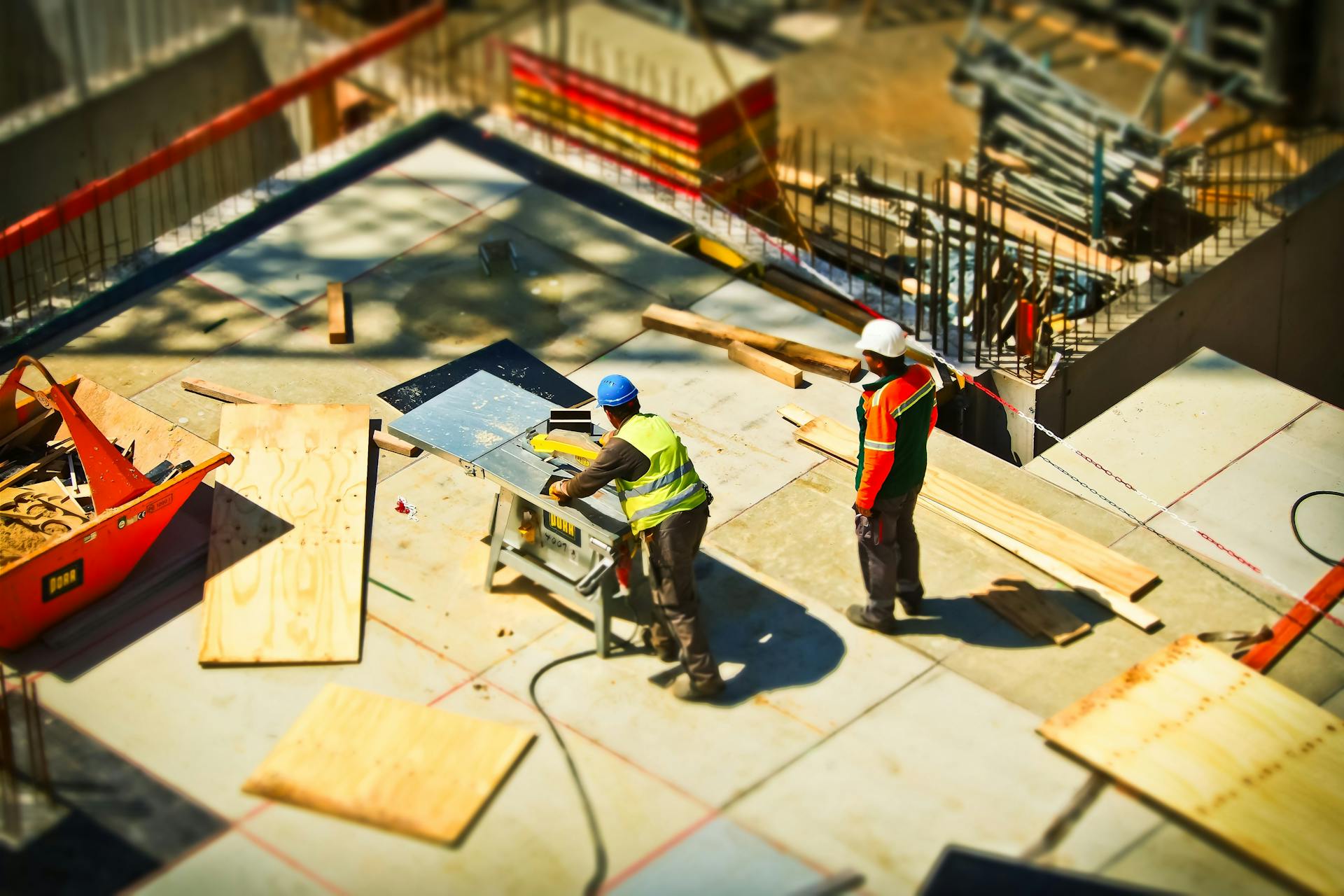 Construction workers engaging in tasks at an outdoor building site with safety hats and equipment.