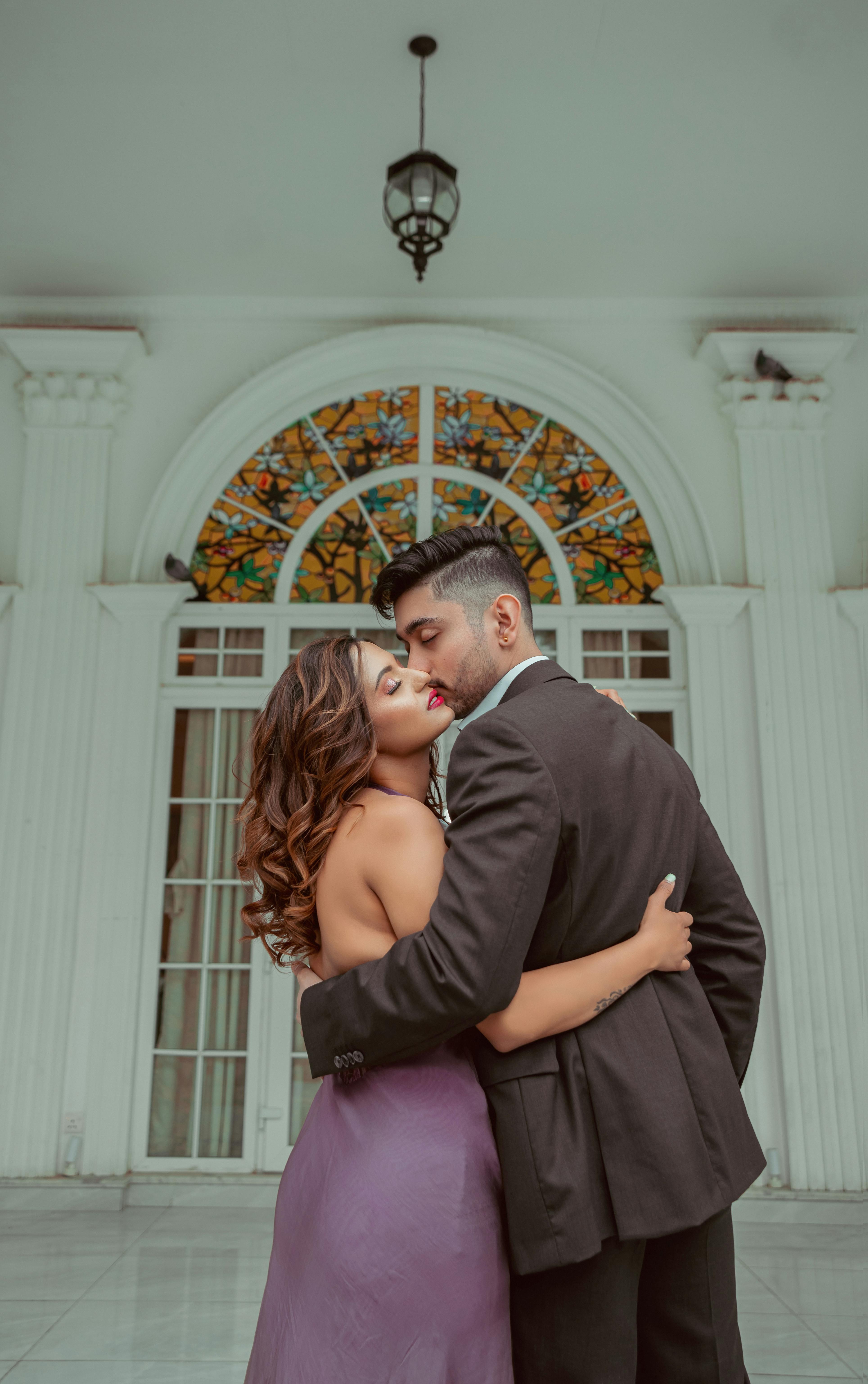 https://images.pexels.com/photos/15930855/pexels-photo-15930855/free-photo-of-photo-of-a-couple-kissing-and-cuddling-in-front-of-a-white-building.jpeg