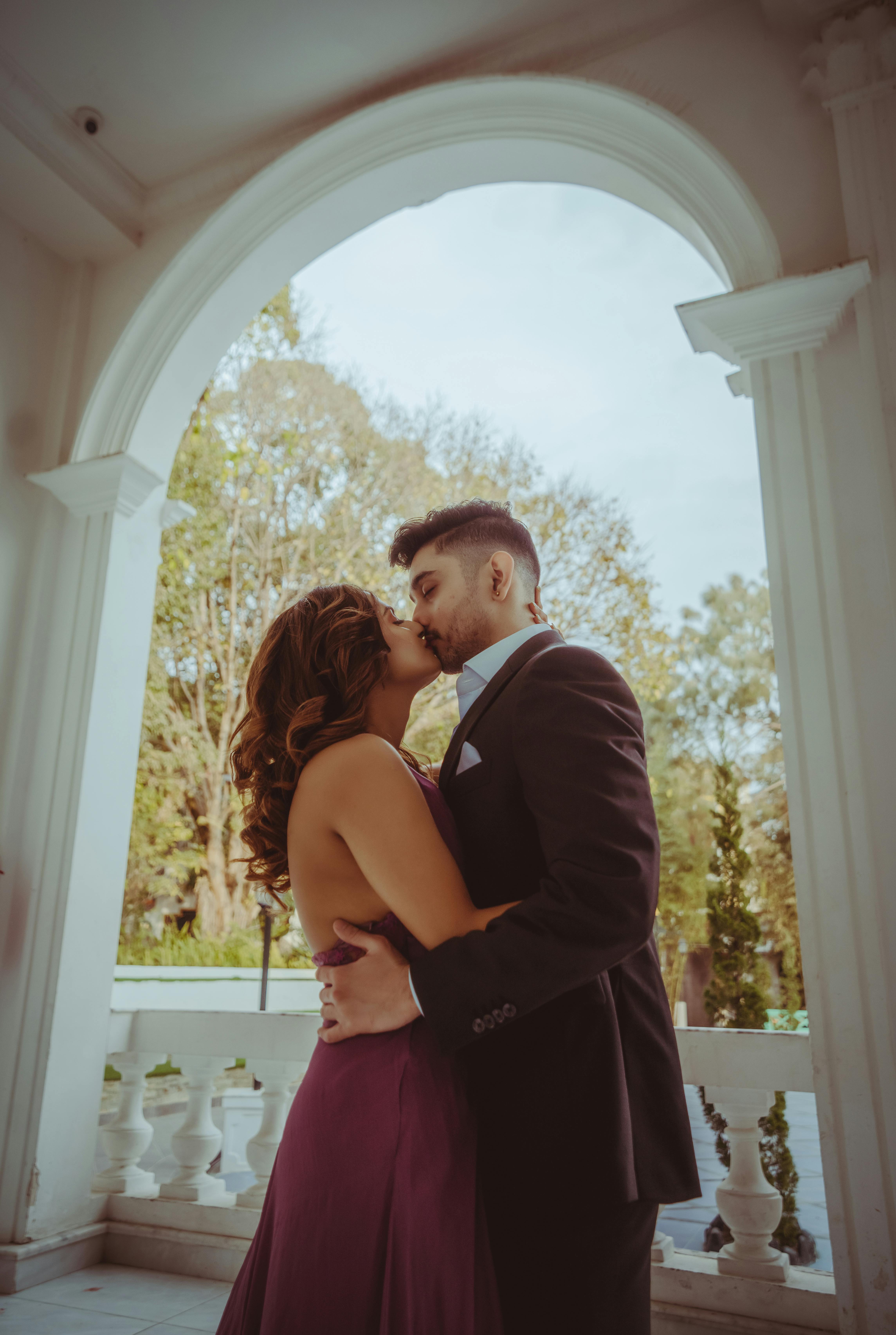 https://images.pexels.com/photos/15930871/pexels-photo-15930871/free-photo-of-photo-of-a-couple-kissing-under-an-arch.jpeg