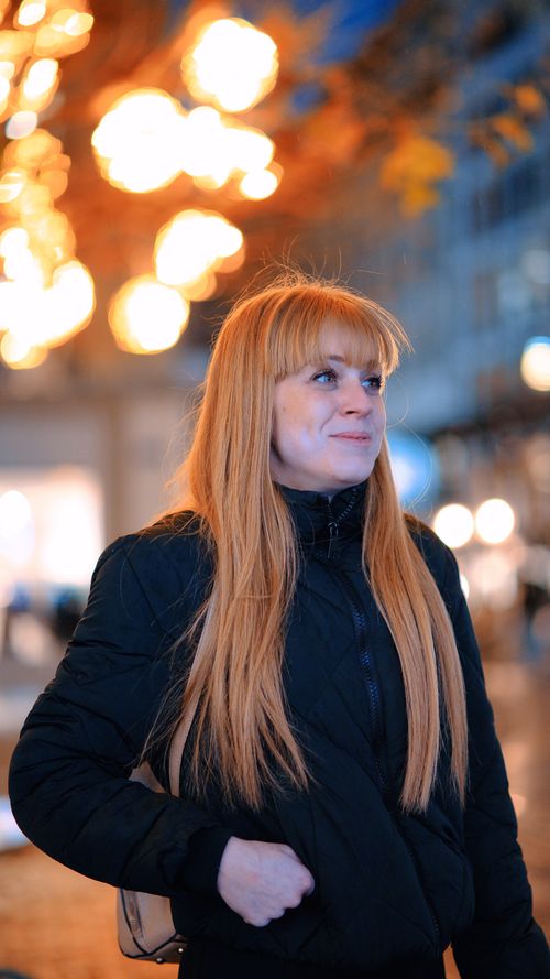 Free A fashionable woman with long blonde hair stands in city lights, exuding confidence. Stock Photo