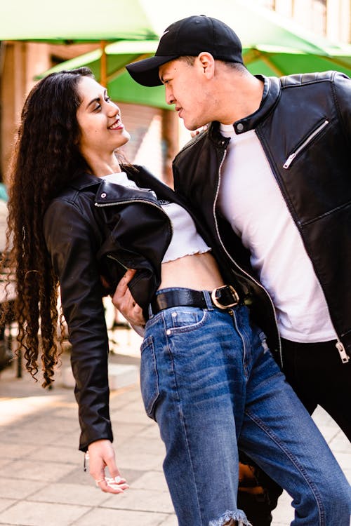 Free A Young Couple Hugging while Standing on a Sidewalk  Stock Photo