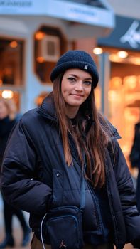Smiling woman in warm clothing on a city street during winter.