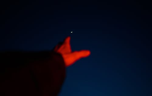 Hand Raised towards Moon at Night