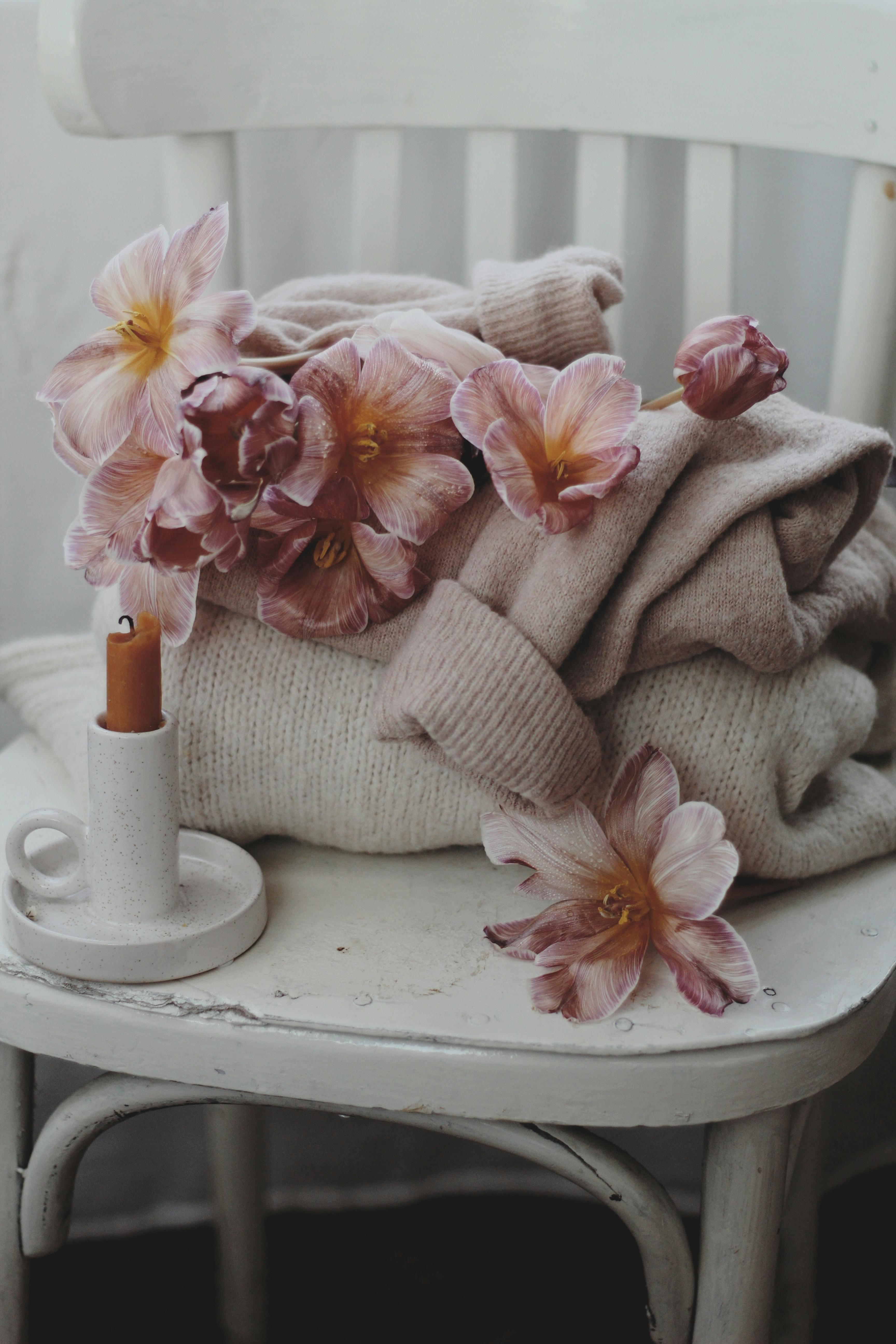 A warm and cozy scene with a sweater adorned with pink flowers on a rustic chair.