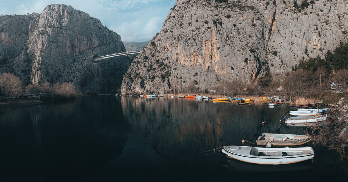 Boats Moored near Rocks around Lake · Free Stock Photo