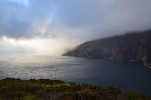 Dramatic cloudy view of Slieve League cliffs and ocean at twilight.