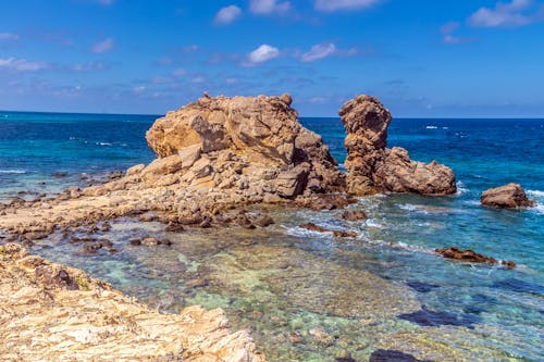 A Rock Formation on the Shore and the Seascape under a Blue Sky 