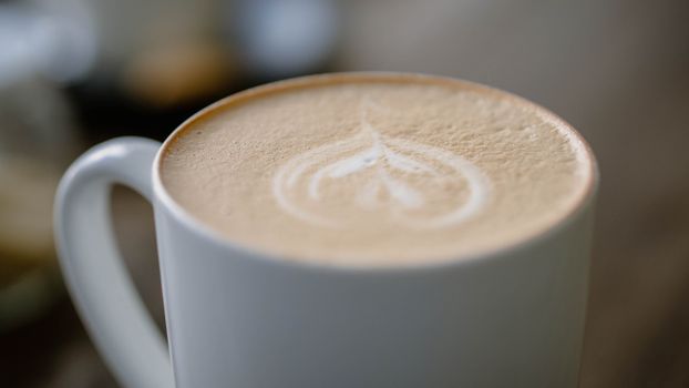 Elegant cappuccino featuring delicate latte art in a white mug, showcasing coffee craft.