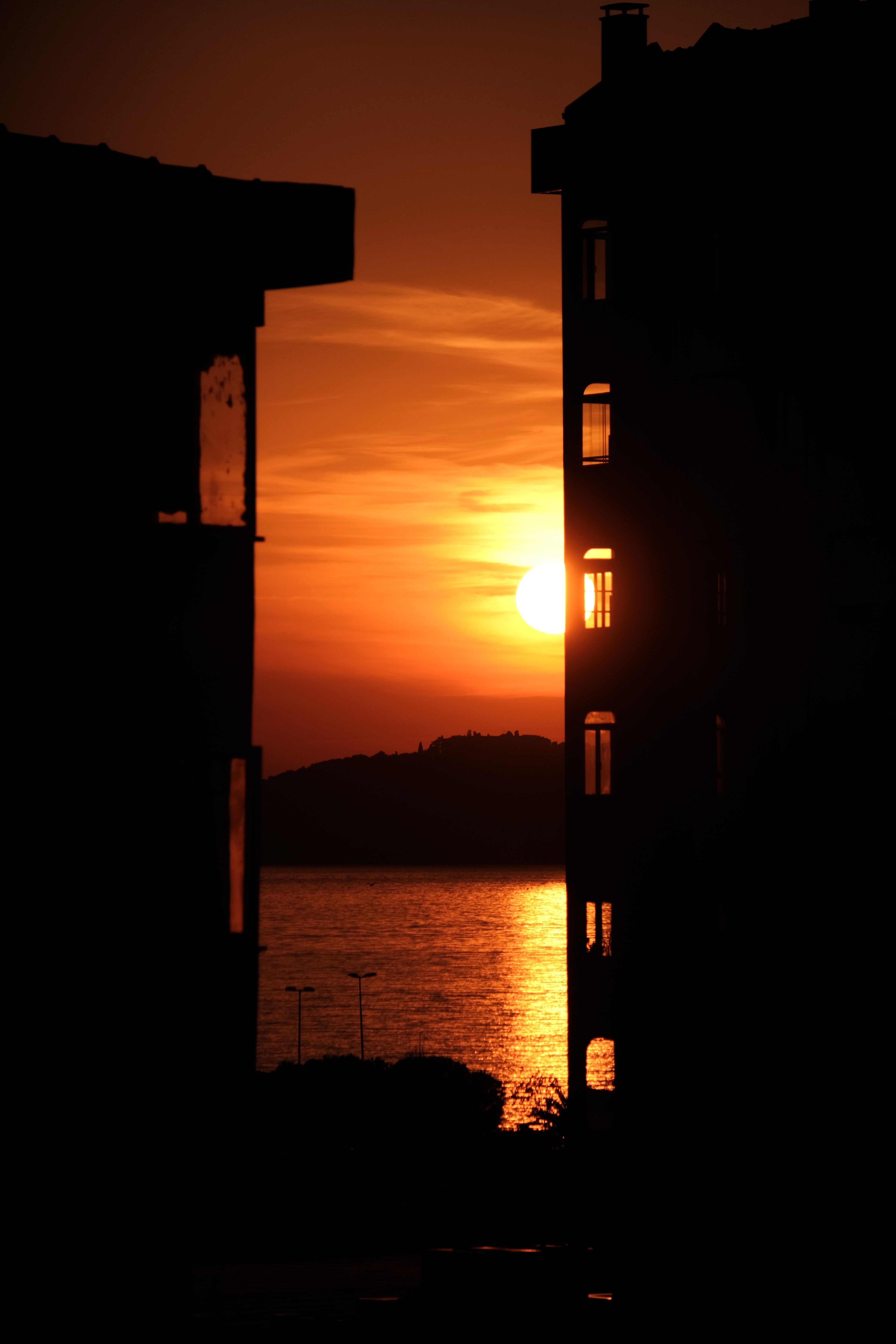 Buildings Silhouette on Sea Coast at Sunset · Free Stock Photo