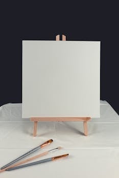 A blank canvas on an easel with paintbrushes symbolizing creativity. Perfect for art projects.