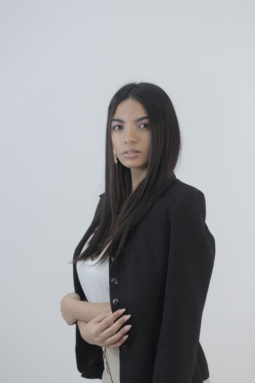 Free A sophisticated portrait featuring a woman posing in a black suit against a white background. Stock Photo