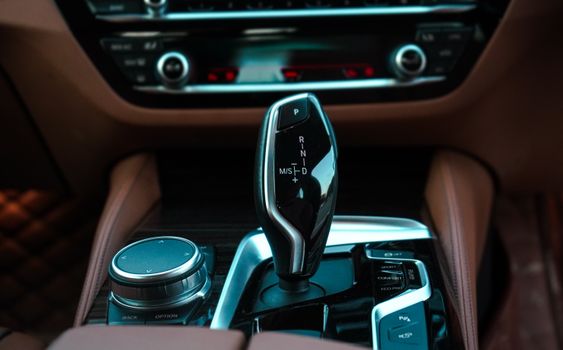 Close-up view of a modern car interior featuring a sleek gear lever and control panel. Ideal for automotive themes.