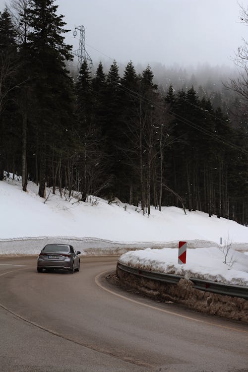 Car on the Bend of a Snow-cleared Mountain Road Between Snowdrifts