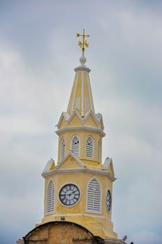 A beautiful view of the historic Torre del Reloj in Cartagena, showcasing its distinctive architecture against a cloudy sky.
