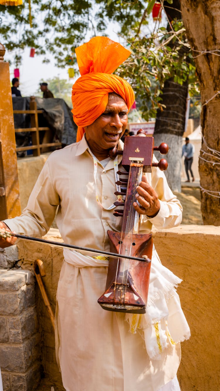 Man In Traditional Headwear Playing On Musical Instrument