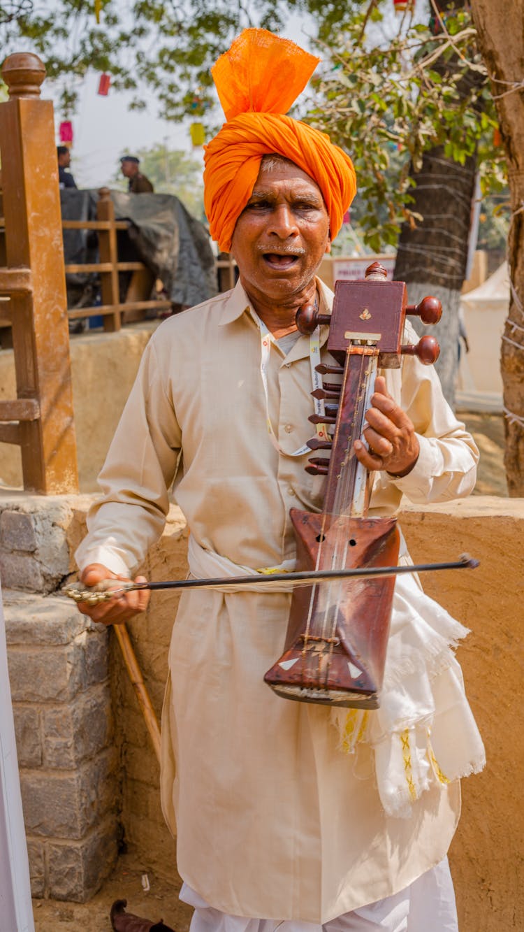 Man In Traditional Clothes And Headwear Playing Musical Instrument