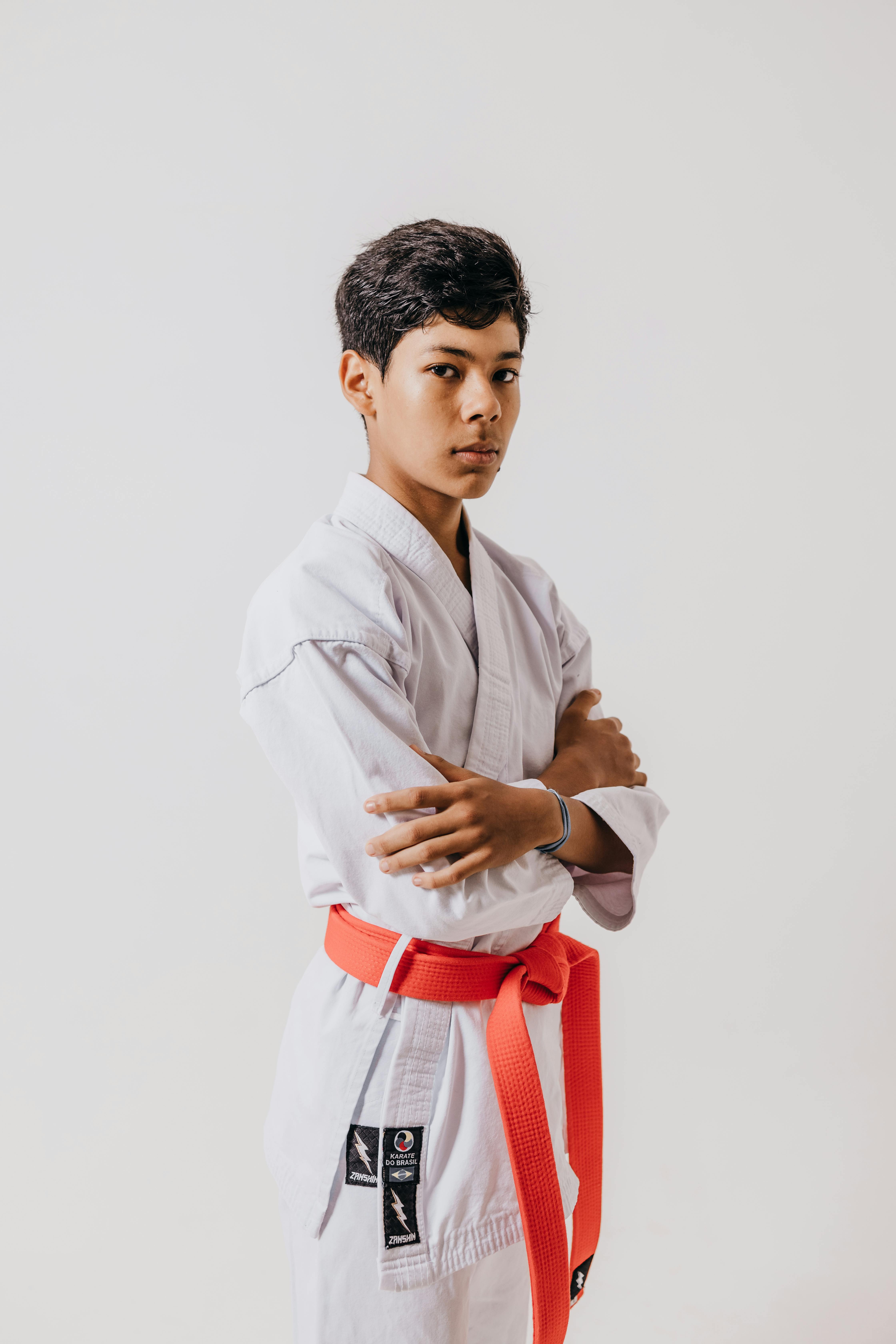 Studio portrait of a teenager in a karate gi with a red belt, showcasing discipline and focus.