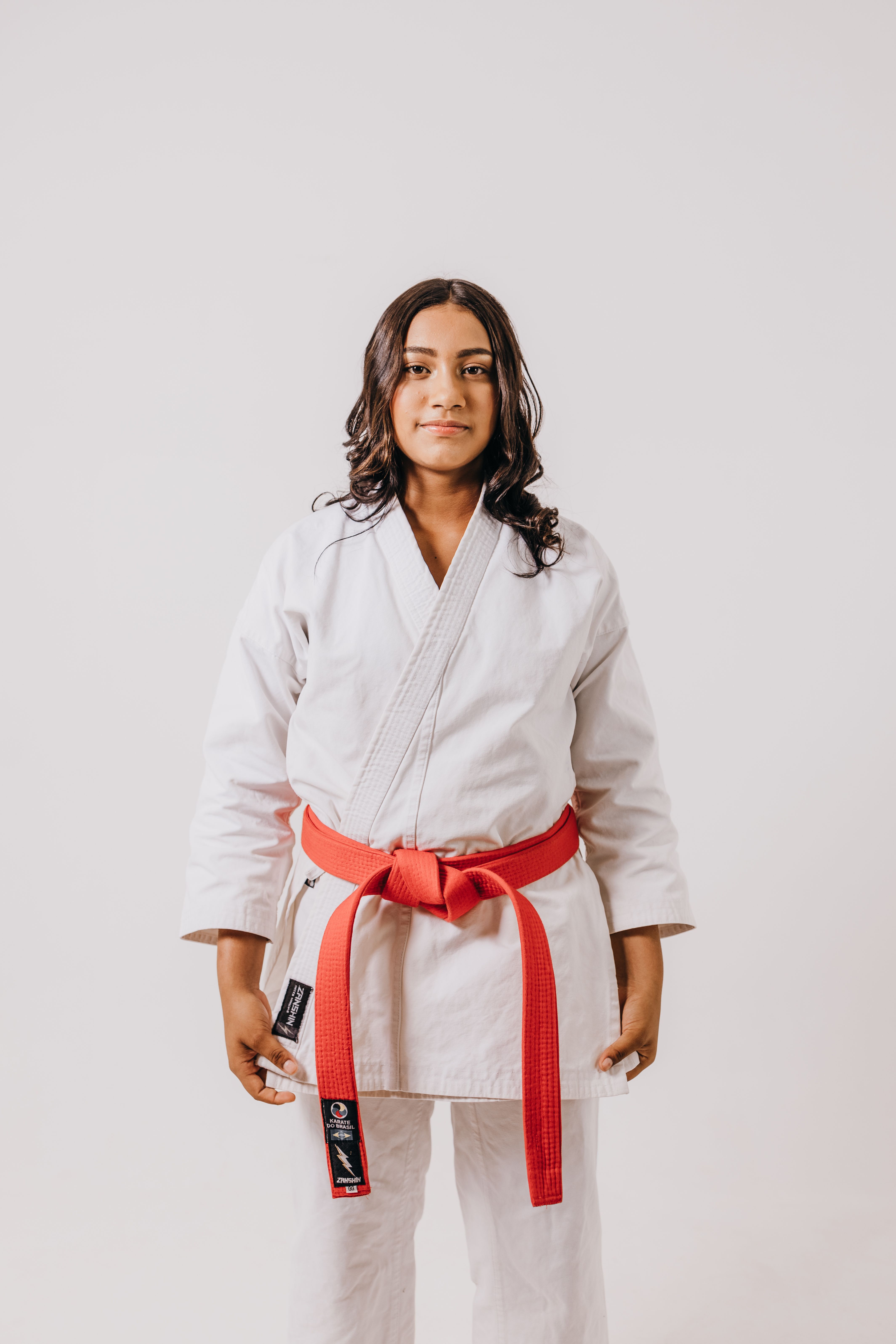 Portrait of a young woman karate practitioner wearing a red belt in a studio setting.