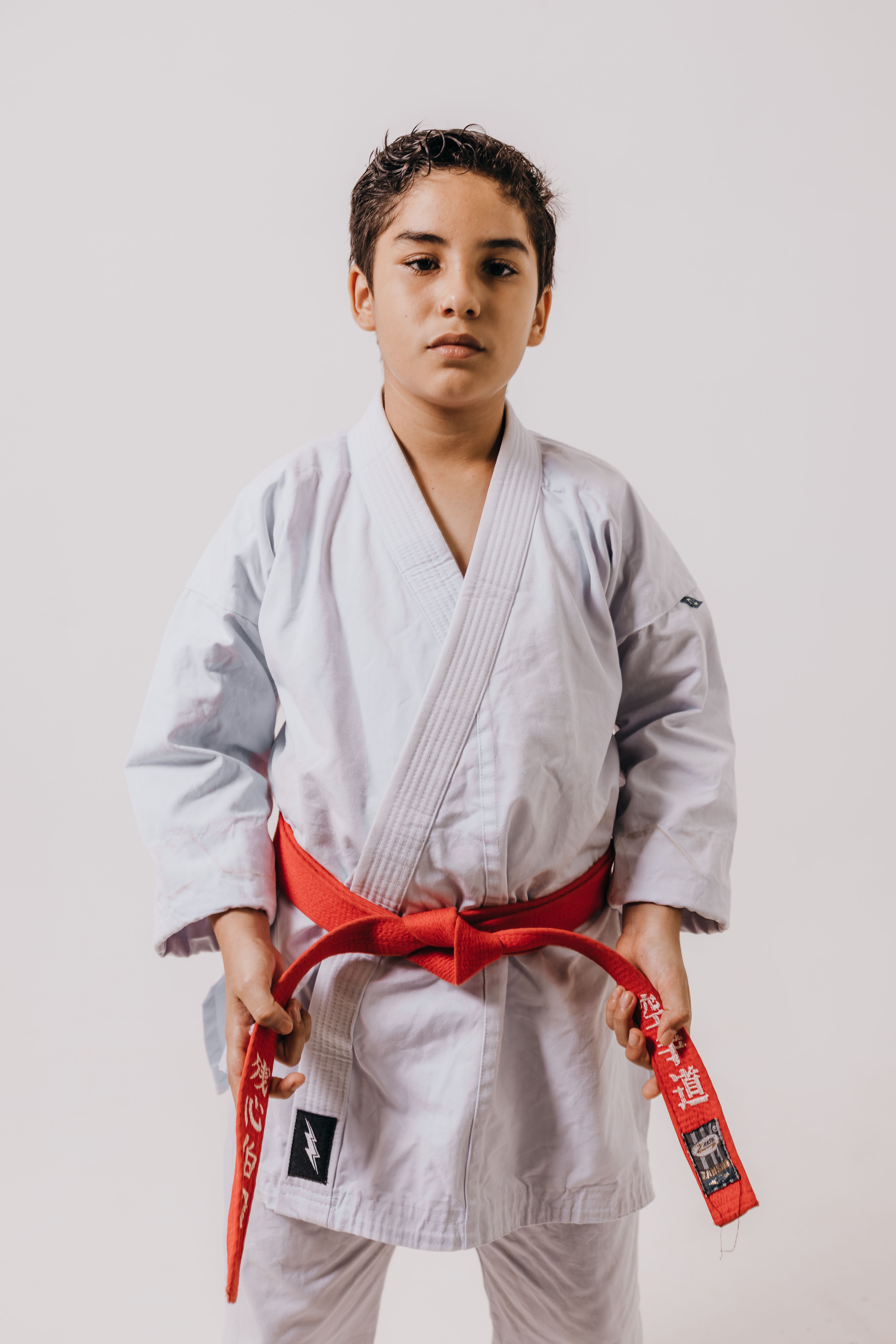 Teenage boy in martial arts gi with red belt posing for portrait.