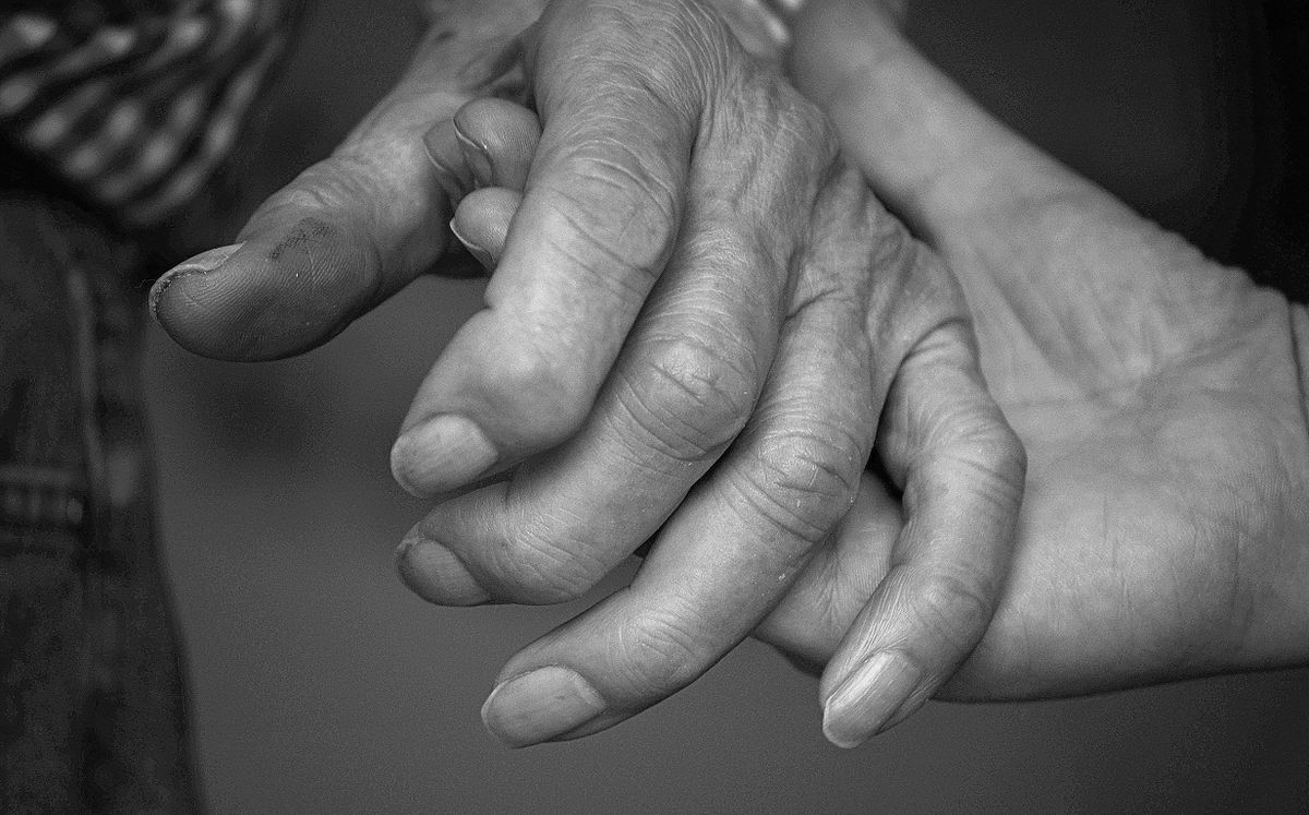 Close-up black and white photo of an elderly couple holding hands