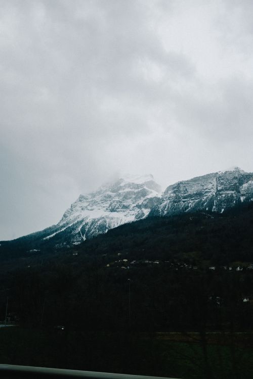 Free A scenic view of a snow-capped mountain partially obscured by clouds, creating a dramatic and moody landscape. Stock Photo