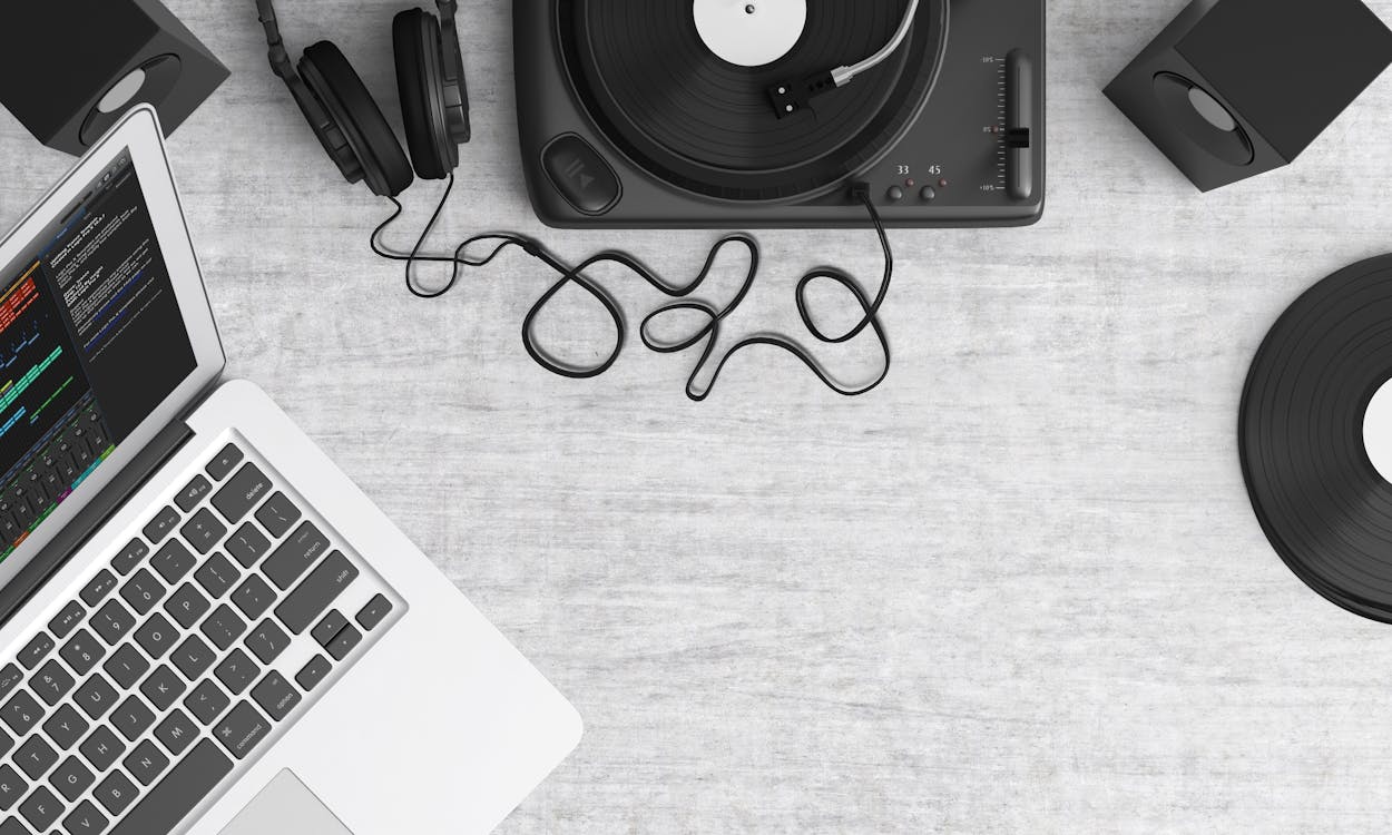 免费 Macbook Pro在灰色桌子上的黑色耳机旁边 素材图片