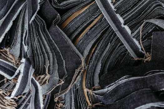 An artistic close-up of layered denim fabric strips showcasing texture and detail.